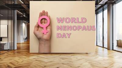 World Menopause Day. Woman holding female gender sign on beige background, top view Wall mural