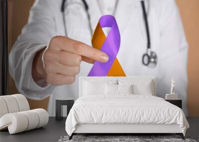 World Psoriasis Day. Doctor with orange and orchid ribbon as symbol of support on dark beige background, closeup Wall mural