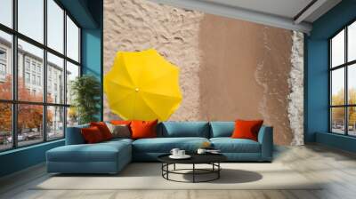 Yellow beach umbrella on sandy coast near sea, top view Wall mural