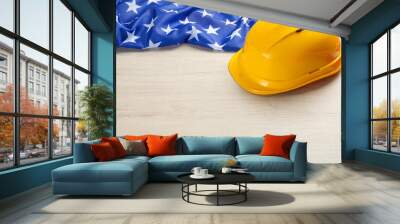 Yellow protective hard hat and American flag on white wooden table. Space for text Wall mural