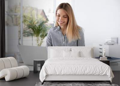 Young businesswoman using laptop at table in office Wall mural