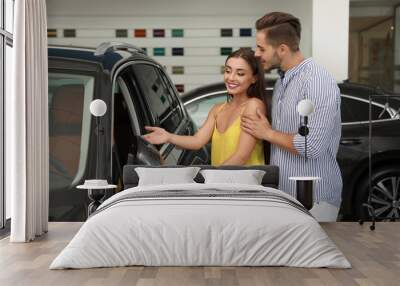 Young couple choosing new car in salon Wall mural