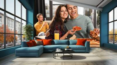 Young couple eating delicious pizza in cafe Wall mural