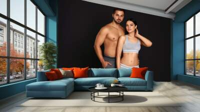 Young couple in grey sportive underwear on black background Wall mural