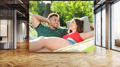 Young couple resting in comfortable hammock at green garden Wall mural