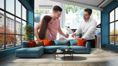 Young couple signing documents in car salon Wall mural