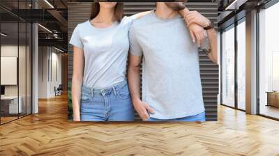 Young couple wearing gray t-shirts near wall on street. Wall mural