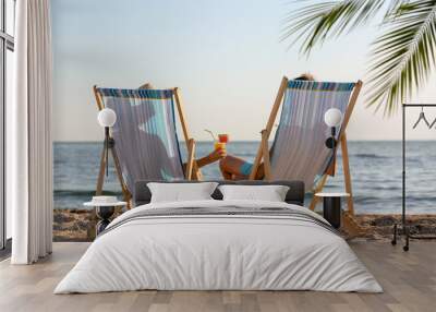 Young couple with cocktails in beach chairs at seacoast Wall mural