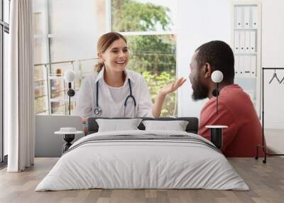 Young doctor speaking to African-American patient in hospital Wall mural