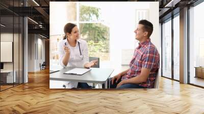 Young doctor speaking to patient in hospital Wall mural