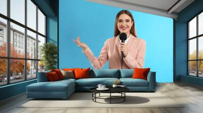 Young female journalist with microphone on blue background Wall mural