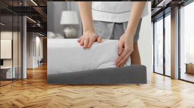 Young maid making bed in hotel room, closeup Wall mural