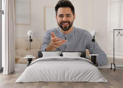 Young man conducting webinar at desk in room Wall mural