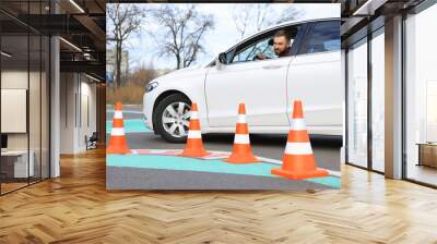 Young man in car on test track with traffic cones. Driving school Wall mural