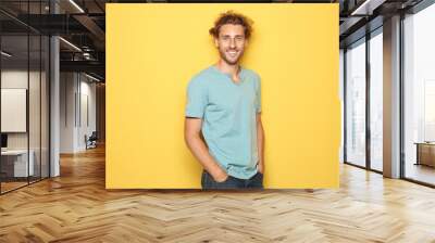 Young man in casual clothes posing on color background Wall mural