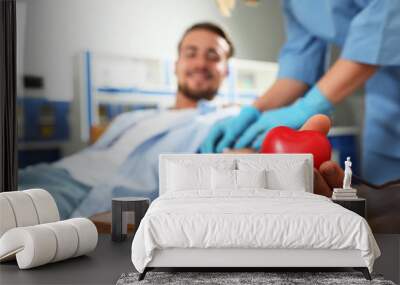 Young man making blood donation in hospital, focus on hand Wall mural