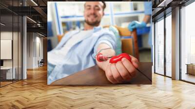 Young man making blood donation in hospital, focus on hand Wall mural