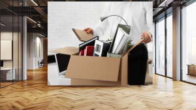 Young man packing stuff in box at office, closeup Wall mural