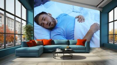 Young man snoring while sleeping in bed at night. Sleep disorder Wall mural