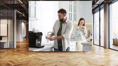 Young man using modern coffee machine in kitchen Wall mural