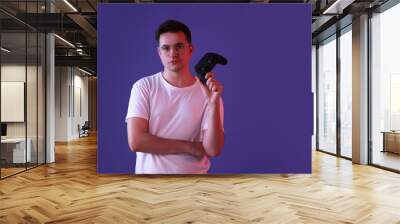 Young man with controller on violet background, space for text Wall mural