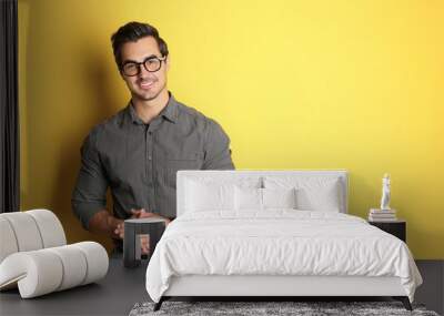 Young man with glasses on yellow background. Space for text Wall mural