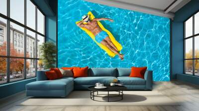 Young man with inflatable mattress in swimming pool, top view. Space for text Wall mural