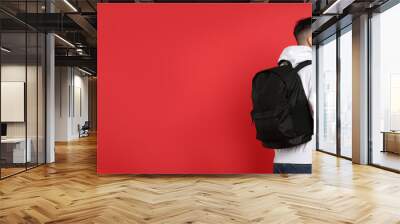 Young man with stylish backpack on red background, back view. Space for text Wall mural