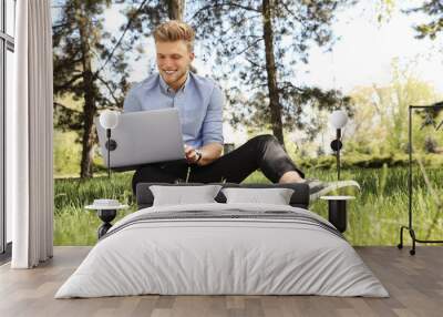 Young man working on laptop in park Wall mural