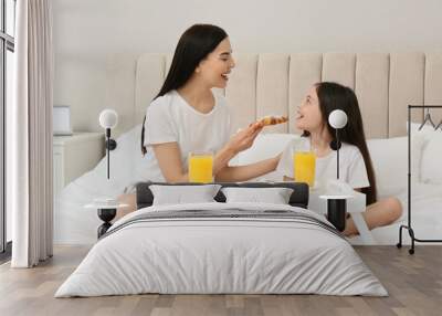 Young mother and her daughter having breakfast on bed at home Wall mural