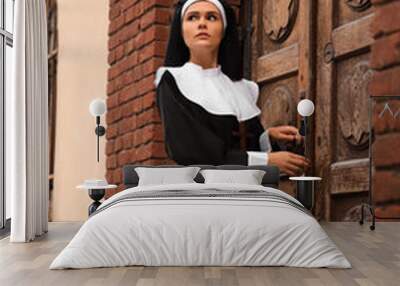 Young nun near wooden door of old building outdoors Wall mural