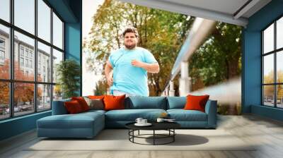 young overweight man running outdoors. fitness lifestyle Wall mural