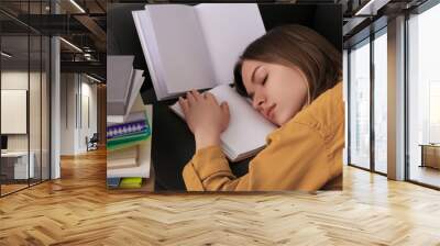 Young tired woman sleeping near books on couch Wall mural