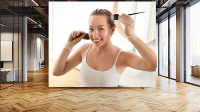 Young woman applying dye on hairs in bathroom Wall mural