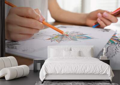 Young woman coloring antistress page at table indoors, closeup Wall mural