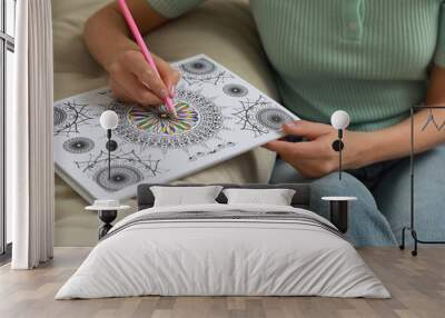 Young woman coloring antistress page near sofa, closeup Wall mural