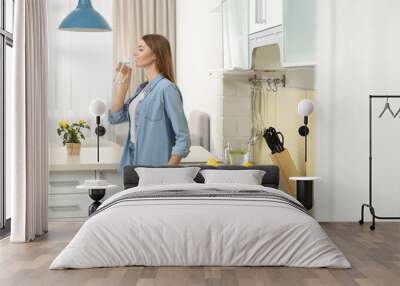 Young woman drinking lemon water in kitchen Wall mural