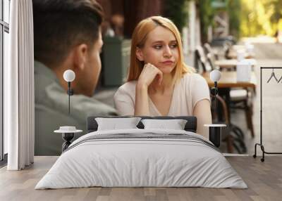 Young woman getting bored during first date with man at outdoor cafe Wall mural