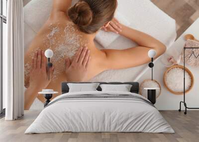 Young woman having body scrubbing procedure with sea salt in spa salon, top view Wall mural