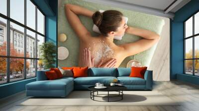 Young woman having body scrubbing procedure with sea salt in spa salon, top view Wall mural