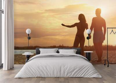 Young woman in bikini spending time with her boyfriend on beach. Lovely couple Wall mural