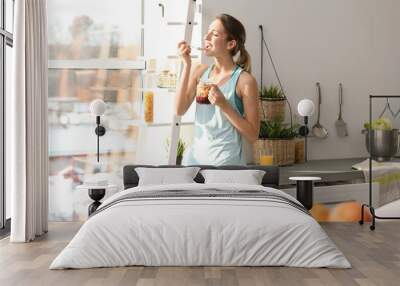 Young woman in fitness clothes having healthy breakfast at home Wall mural