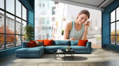 Young woman in fitness clothes having healthy breakfast at home Wall mural