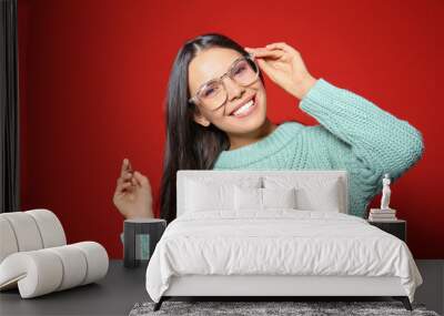 Young woman in warm sweater on red background Wall mural