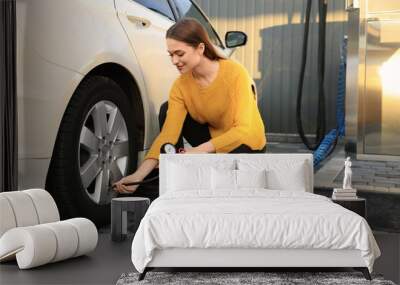 Young woman inflating tire at car service Wall mural