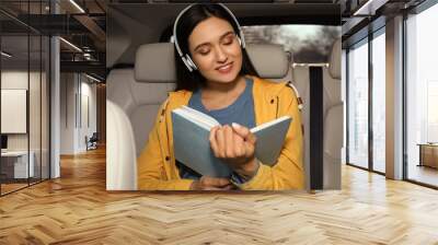 Young woman listening to audiobook in car Wall mural