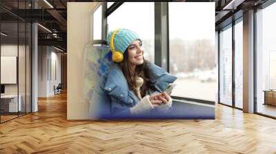 Young woman listening to music with headphones in public transport Wall mural