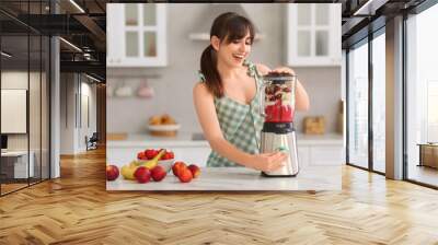 Young woman making delicious smoothie with blender at white marble table in kitchen Wall mural