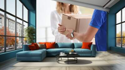 Young woman receiving parcel from courier indoors Wall mural