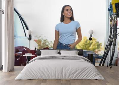 Young woman refueling car at self service gas station Wall mural